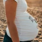 Een stralende zwangere vrouw poseert op de foto &ndash; let op de verschijning rechts!