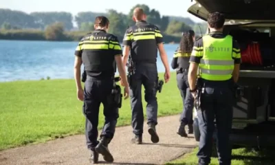Politieagenten lopen langs een plas naar een politievoertuig