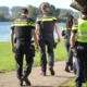 Politieagenten lopen langs een plas naar een politievoertuig